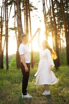 Couple dancing joyfully in a sun-drenched forest during golden hour Stock Photos