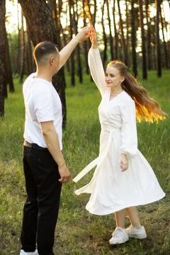 Couple dancing joyfully in a sunlit forest during golden hour Stock Photos