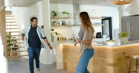Couple dancing in modern kitchen with man entering from left, holding hands, Stock Footage 344327818