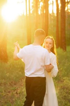 Couple dancing romantically in a sun-drenched forest during golden hour Stock Photos