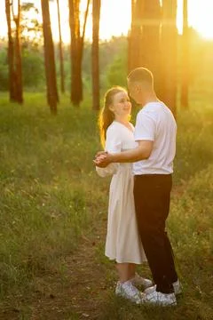 Couple dancing in a sun-drenched forest during golden hour Stock Photos