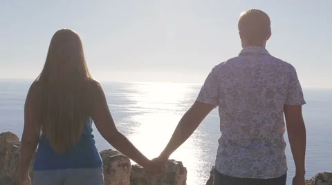 Couple on a date holding hands the background of the ocean solar flare Stock Footage 68318723