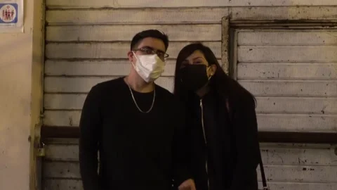 A couple at dawn after going to the disco waving to the camera with a face mask Stock Footage 160985158