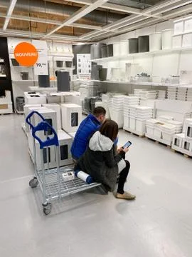 Couple deciding inside IKEA store what to buy sitting on a shopping car with Fotos de archivo