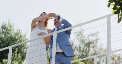 Couple on deck man reaching taking woman's hand twirling under cable railing Stock Footage 336716481