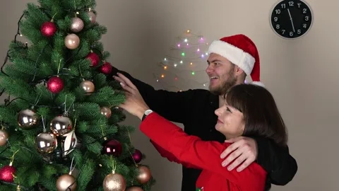 A couple is decorating a Christmas tree with ornaments Stock Footage 319829663