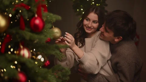 Couple decorating a Christmas tree in a warm festive atmosphere. 스톡 동영상 322666836