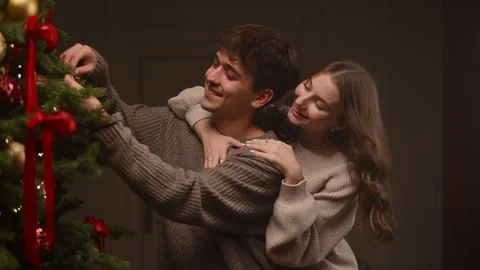 Couple decorating a Christmas tree in a warm slow-motion holiday moment. Stock Footage 322670369