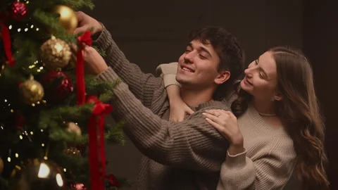 Couple decorating a Christmas tree in a warm slow-motion holiday moment. Stock Footage 322670950