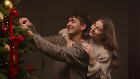 Couple decorating a Christmas tree in a warm slow-motion holiday moment. Stock Footage 323170195
