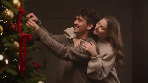 Couple decorating a Christmas tree in a warm slow-motion holiday moment. Stock Footage 323172450
