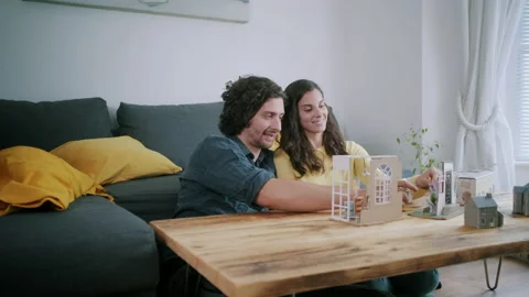 Couple decorating miniature model house on table Stock Footage 130324844