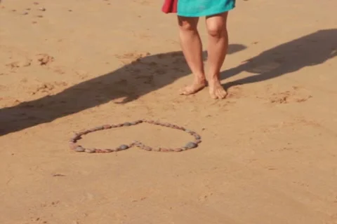 Couple destroying heart shape made of stones on the sand NTSC Stock Footage 10823529