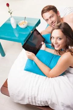 Couple with digital tablet lying on bed Stock Photos