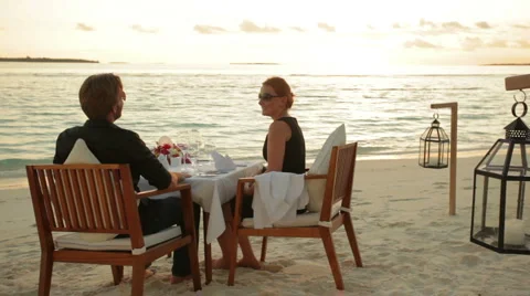 Couple dining in front of the ocean at sunset Stock Footage 1018411