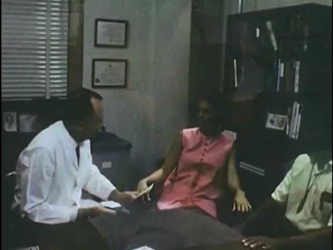 A couple discusses birth control options with a doctor in the 1970s. Stock-Footage 74934518
