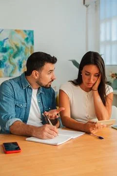 Couple discussing notes at a table with notebook and pen during collaborative Stock Photos
