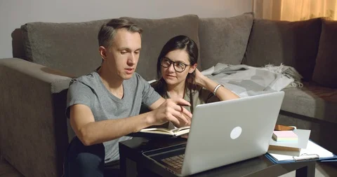 Couple discussing a project or design of a new apartment working on a laptop Stock Footage 129899479
