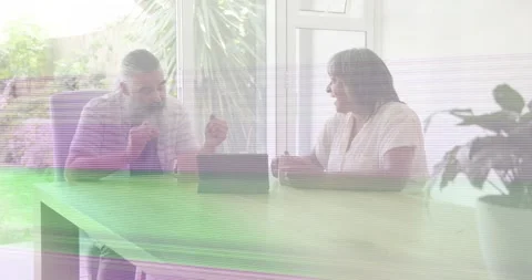 Couple discussing tech at table, tablet; glitches crossing frames, guest Stock Footage 334109025