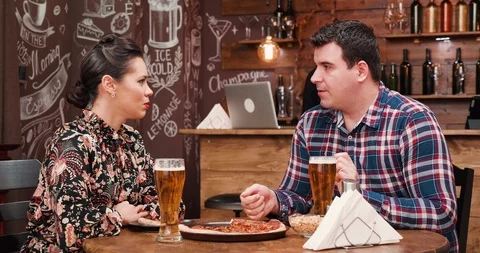 Couple discussing while drinks beer and eats pizza Stock Footage 101277054