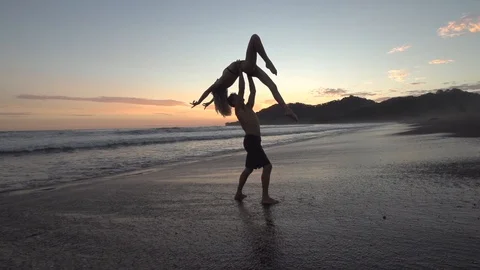 Couple Do Acrobatic Partner Lift in The Sunset in Slow Motion Stock Footage 87723615