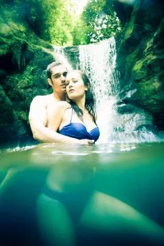 Couple Doing Embracing Under Waterfall Stockfoto's