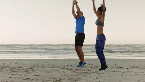 Couple doing jumping jacks on beach intense workout Stock Footage 76521493