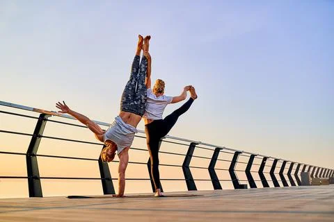 Couple doing practicing yoga together on nature outdoors . Morning exercises at Stock Photos