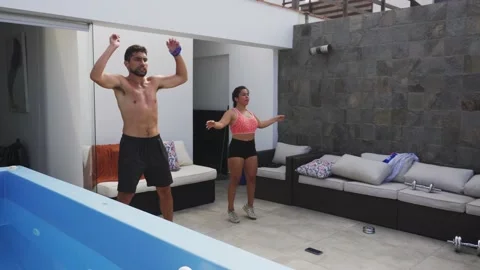 A couple doing pull-pull exercises on a terrace of a beach house with their cell Vidéo 189136487