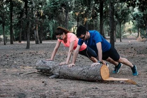 Couple doing push-ups on a log in a park Stock Photos