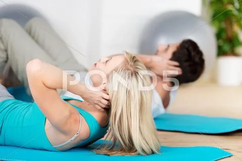 Couple doing sit ups on exercise mat Stock Photos