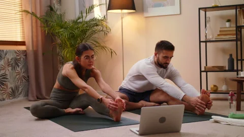 Couple Doing Stretching Exercise At Home On Mat Watch Fitness Video On Laptop Stock Footage 146993332