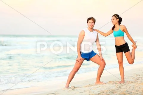 Couple doing stretching exercises workout training on beach Stock Photos
