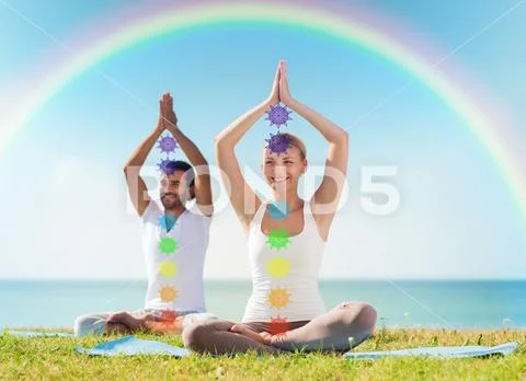 Couple doing yoga in lotus pose with seven chakras Stock Photos