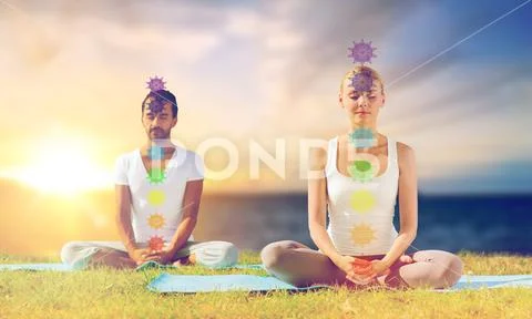Couple doing yoga in lotus pose with seven chakras Stock Photos