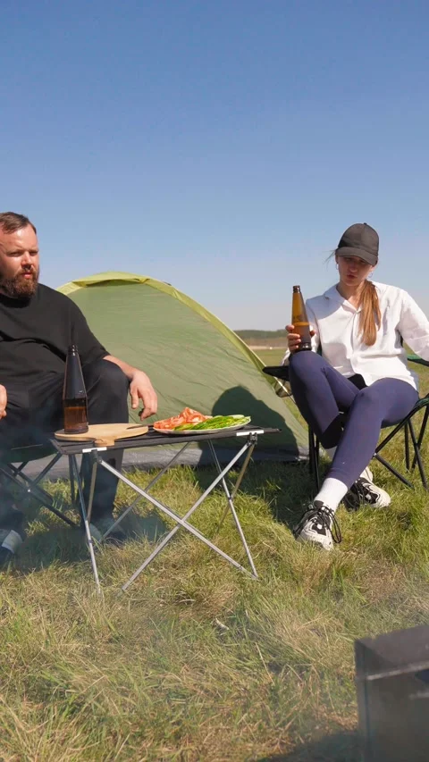 Couple drinking beer during camping trip picnic Stockbeeldmateriaal 344605417