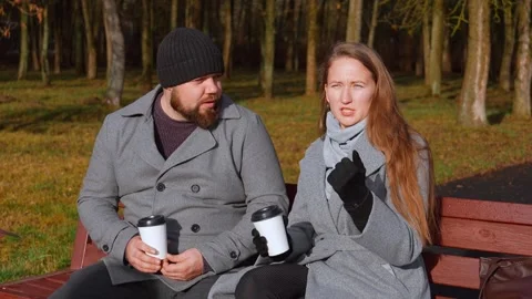Couple drinking coffee and talking on park bench Stock Footage 326149191