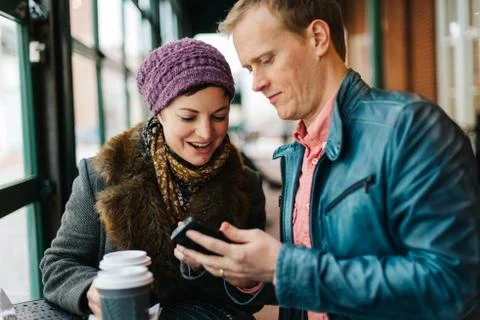 Couple drinking coffee and using a smartphone Stock Photos