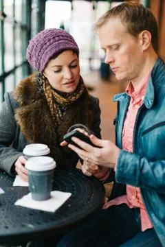 Couple drinking coffee and using a smartphone Stock Photos