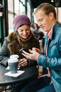 Couple drinking coffee and using a smartphone Stock Photos