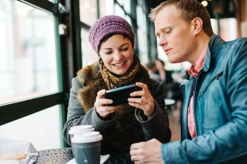 Couple drinking coffee and using a smartphone Stock Photos