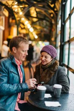 Couple drinking coffee and using a smartphone Stock Photos