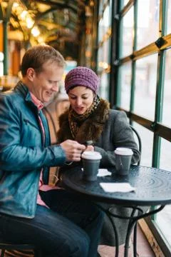 Couple drinking coffee and using a smartphone Stock Photos