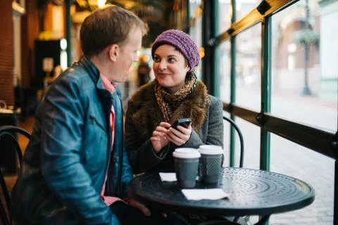 Couple drinking coffee and using a smartphone Stock Photos