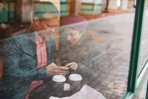 Couple drinking coffee and using a smartphone Stock Photos