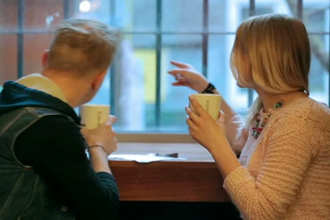 Couple drinking coffee and whispering to each other in the cafe Vídeos de archivo 49471332