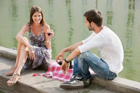 Couple drinking red wine at the ledge of a canal, Paris, Ile-de-France, France 스톡 사진