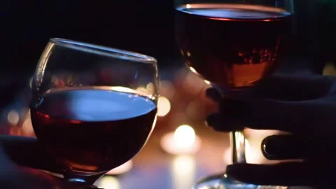 A couple drinking red wine. Light garlands in the background. Celebration. Stock Footage