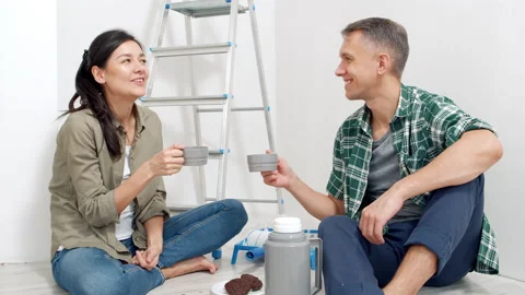 Couple is drinking tea while sitting on the floor resting during renovation. Stock Footage 143553087