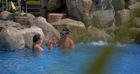 Couple Drinking Tropical Drinks Together in Resort Pool Stock Footage 103220506